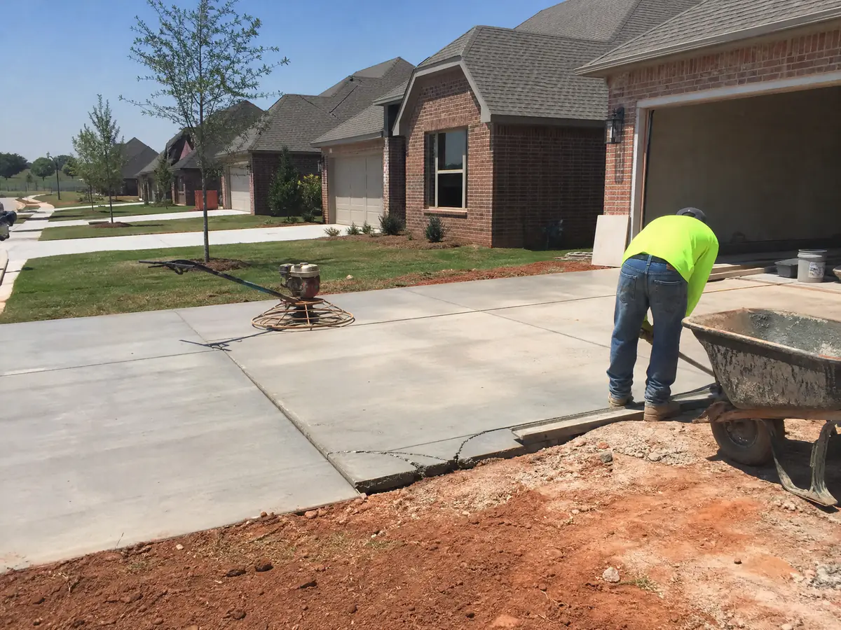 Builder-grade concrete driveway with early corner cracks in a new Mustang, Oklahoma subdivision