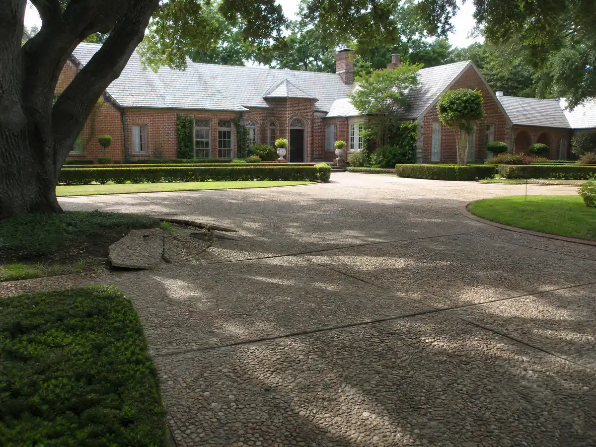 Long circular exposed-aggregate driveway under a mature tree canopy at an estate home in Nichols Hills, Oklahoma