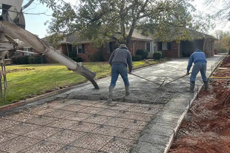 Ready-mix truck chute pouring air-entrained concrete over rebar into a formed driveway in Oklahoma City
